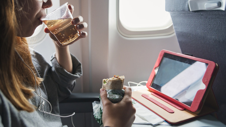 Mujer bebiendo ginger ale en un avión