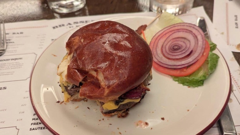 La hamburguesa americana del bar, parcialmente consumida, en un plato junto a la roja, el tomate y la lechuga