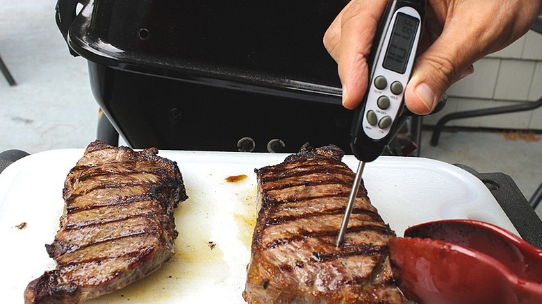 Dos trozos de filete de res sacados de la parrilla, comprobando su temperatura