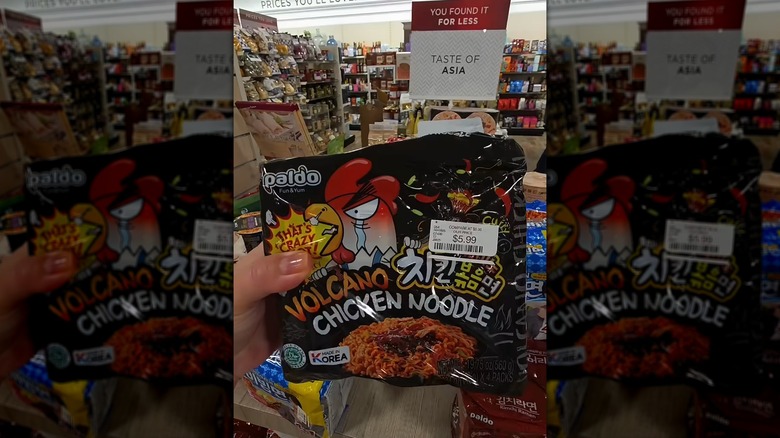 Una mano sosteniendo un paquete de fideos instantáneos con pollo Volcano en HomeGoods