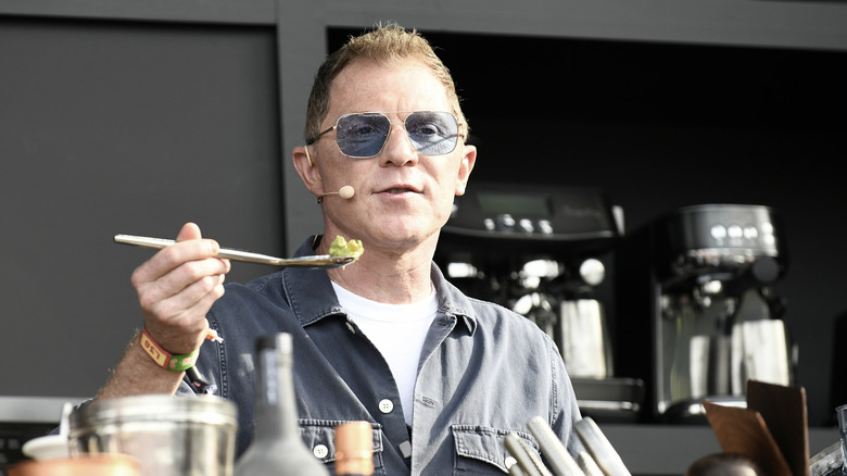 Bobby Flay sosteniendo una cucharada de comida.