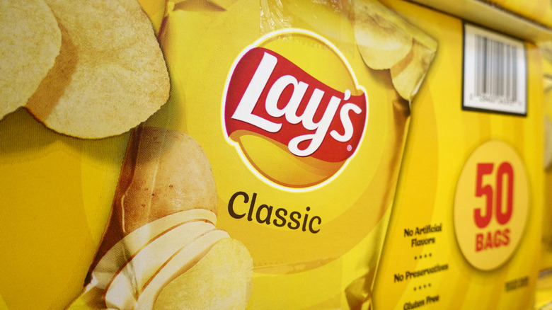 Primer plano de una caja de 50 bolsas de patatas fritas Lay's Classic