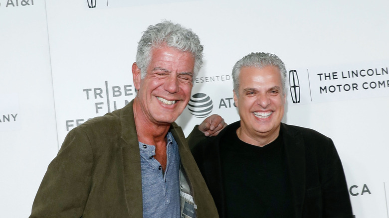 Anthony Bourdain y Eric Ripert riendo en una alfombra roja