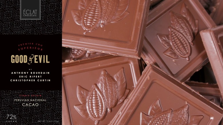 Envase negro para la barra de chocolate Good & Evil, junto a cuadrados de chocolate con diseños de granos de cacao en relieve.
