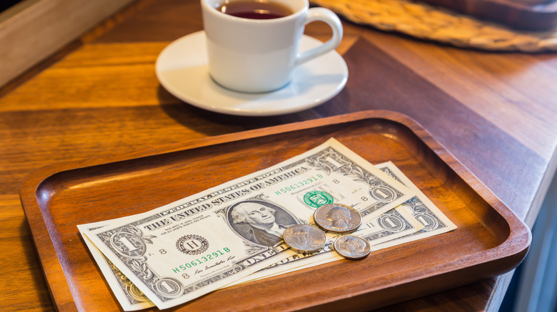 Unos cuantos billetes de un dólar sobre la mesa de una cafetería.