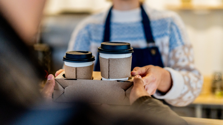 Un cliente acepta un pedido de café para llevar de un barista.