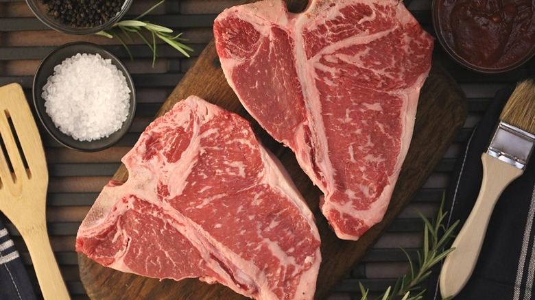 Dos filetes porterhouse, crudos, con un molde de sal en escamas y una cuchara de madera