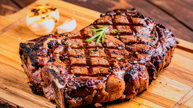 Filete Ribeye a la parrilla, chamuscado con hierbas y ajo, sobre una tabla de madera