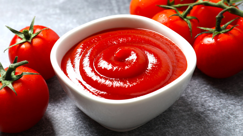 Tazón de ketchup y tomates frescos