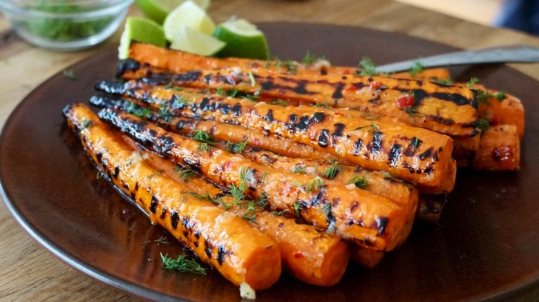 Un plato de zanahorias asadas, espolvoreadas con hierbas verdes frescas.