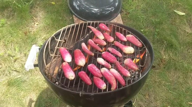 Varios rábanos en rodajas largas cocinados boca abajo en una parrilla de carbón redonda