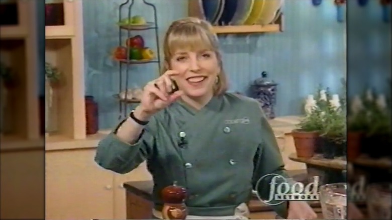 Sara Moulton sonriendo con una chaqueta de chef verde en el set de "Cocinando en vivo"