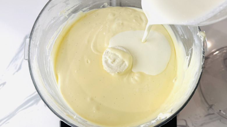Verter crema sobre la masa de tarta de queso en un procesador de alimentos