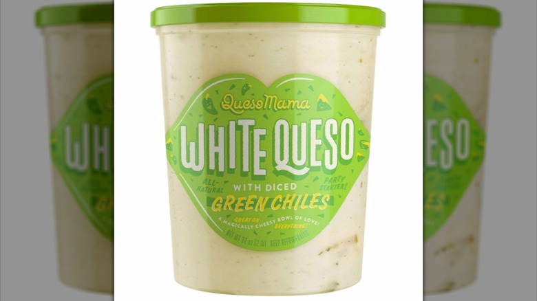 Un recipiente transparente de Queso Mama White Queso con etiqueta y tapa verdes.
