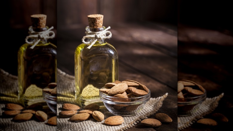 Aceite de almendras en botella y almendras secas.