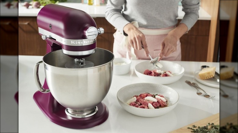 Mujer en la cocina cocinando con una batidora KitchenAid color remolacha