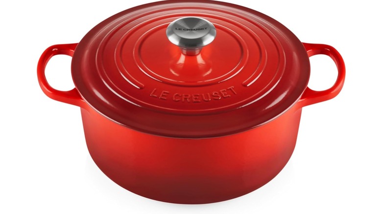 Un horno holandés redondo y rojo de Le Creuset sobre un fondo blanco.