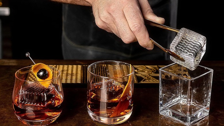 Tres vasos bajo con hielo decorado, la mano pone hielo en un vaso