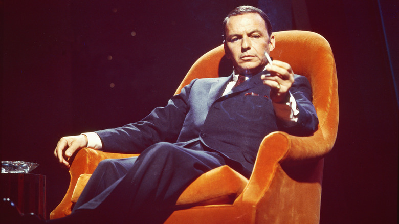 Frank Sinatra posando en un sillón naranja con un cigarrillo