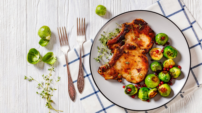Chuletas de cerdo finas y con hueso con coles de Bruselas y cerezas