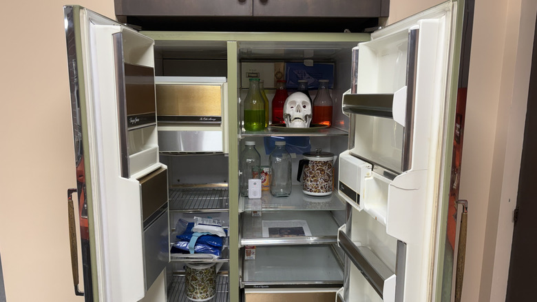 El frigorífico abierto lleno de varias botellas y una calavera falsa blanca.
