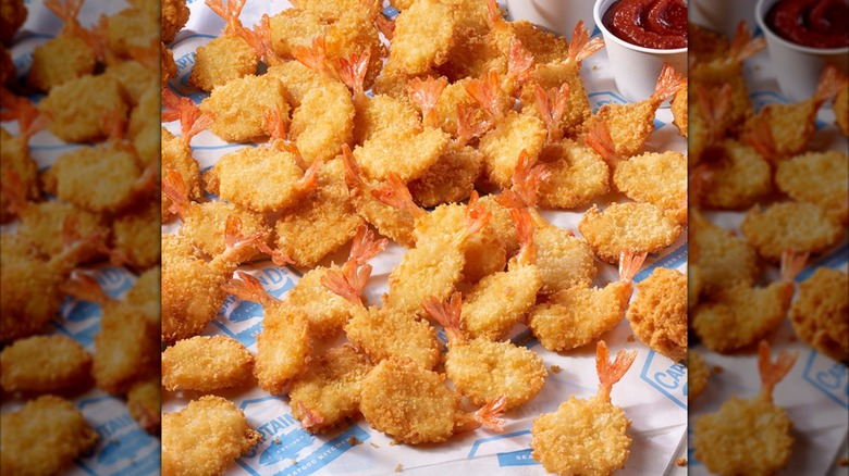 Camarones con mantequilla del Capitán D extendidos sobre papel impreso en un restaurante con salsa.