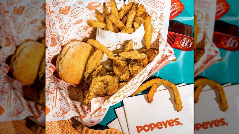 Caja de aparejos de camarones Popeyes Louisiana Kitchen con galleta, papas fritas y salsa para mojar.