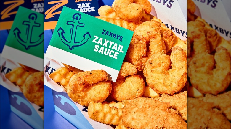 Primer plano de camarones fritos sureños de Zaxby con papas fritas y salsa Zaxtail en una caja.