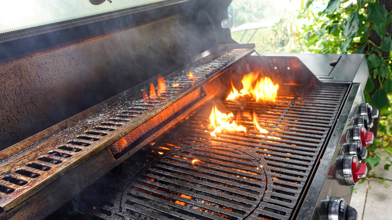 Una parrilla de gas grasienta con las propias parrillas en llamas.