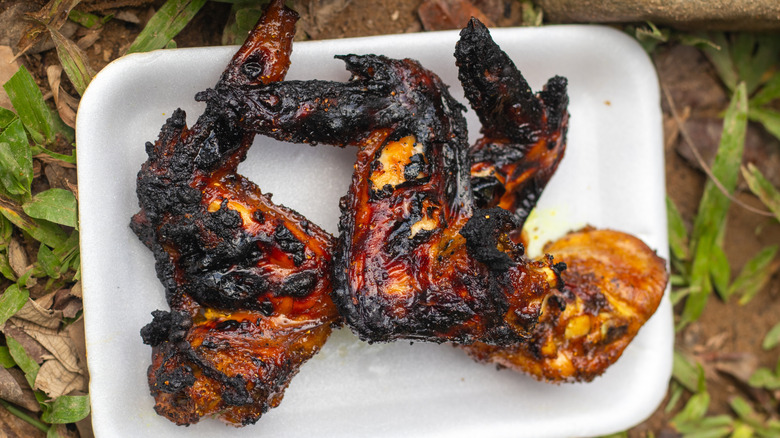 Un plato blanco de alitas de pollo asadas quemadas
