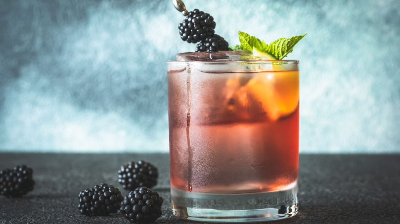 beber en vaso bajo con una ramita de menta y brochetas de moras