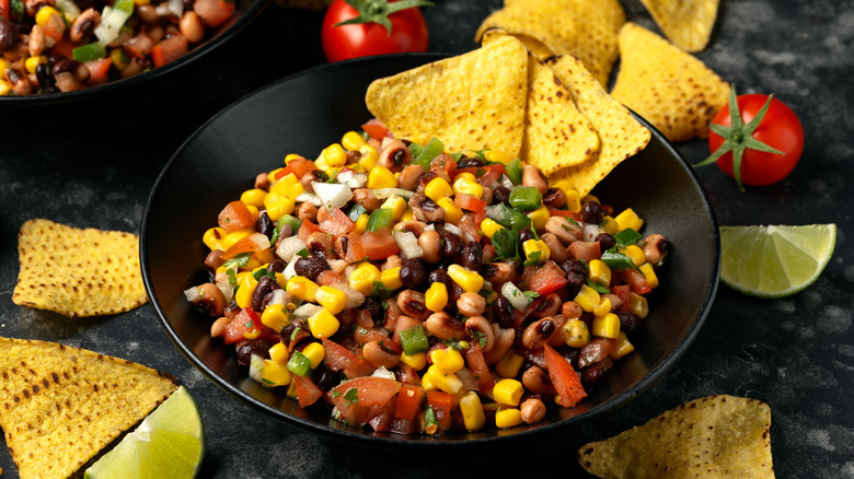 Un plato de salsa de caviar vaquero con frijoles, maíz, tomates y pimientos cortados en cubitos, cilantro y totopos