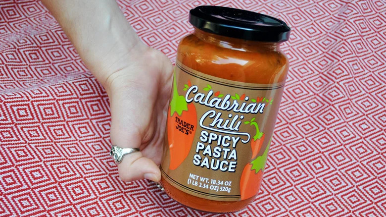 Tarro de salsa de pasta picante de chili de Calabria Trader Joes celebrada sobre un paño rojo