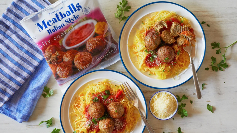 Paquete de albóndigas estilo italiano congeladas de Trader Joes junto a dos tazones de espaguetis y albóndigas