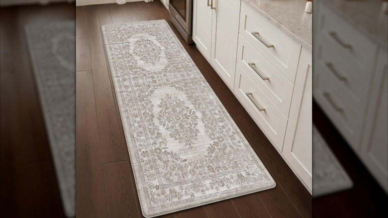 Una alfombra de cocina de color blanquecino con un diseño persa sobre un piso de madera junto a un gabinete blanco