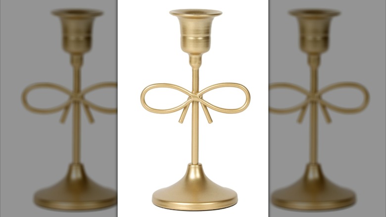 Un candelabro dorado con un lazo en el centro hecho de la propia pieza.