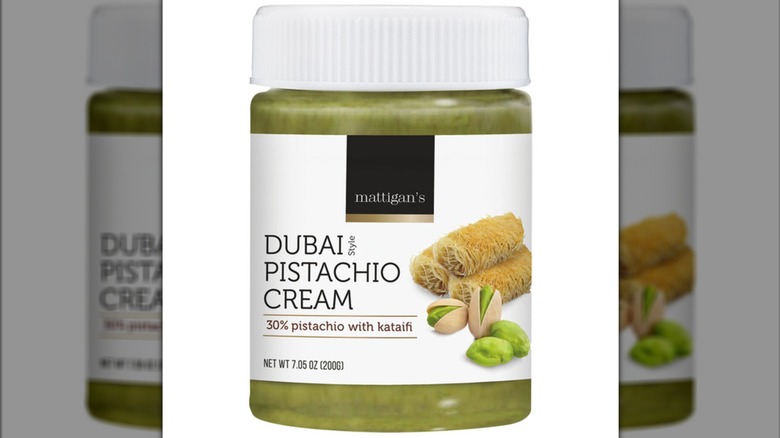 Un frasco transparente con etiqueta blanca de crema para untar de pistacho estilo Dubái de Mattigan, que muestra la extensión verde en el interior