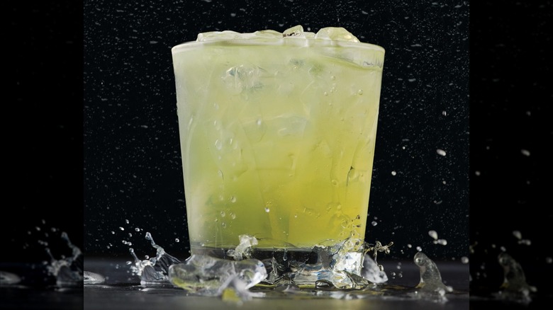 Una margarita en un vaso bajo sobre un fondo negro