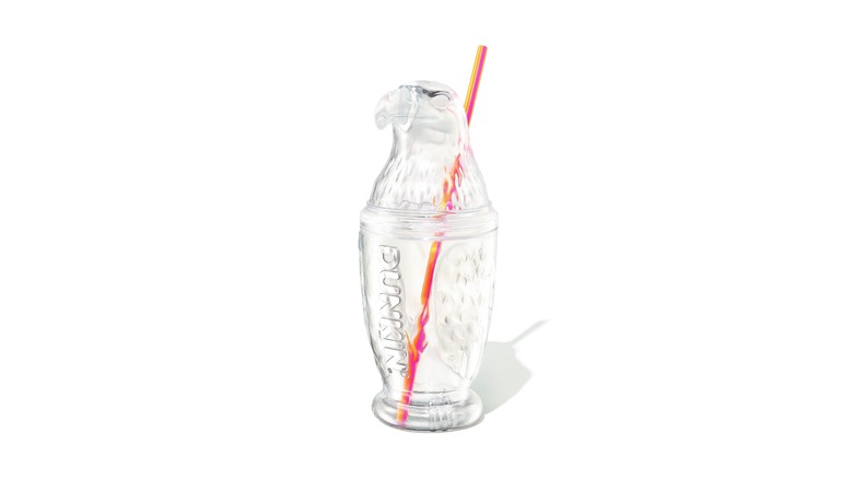 Un vaso transparente con forma de águila calva con el logotipo de Dunkin' en relieve y pajita naranja/rosa.