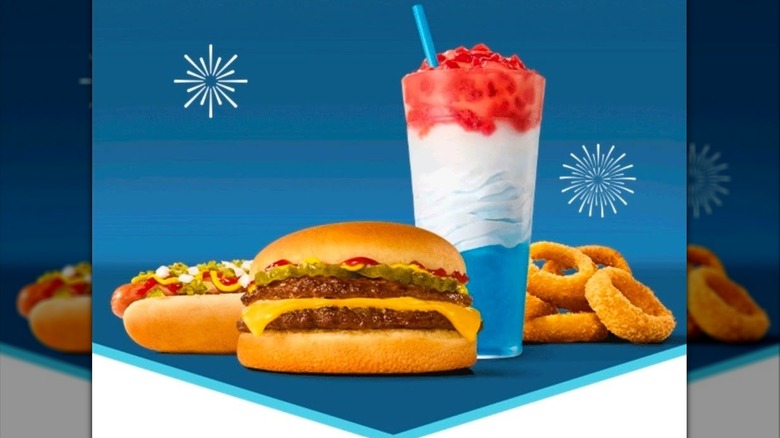Un hot dog cargado, una hamburguesa doble con queso, aros de cebolla y un granizado rojo, blanco y azul.