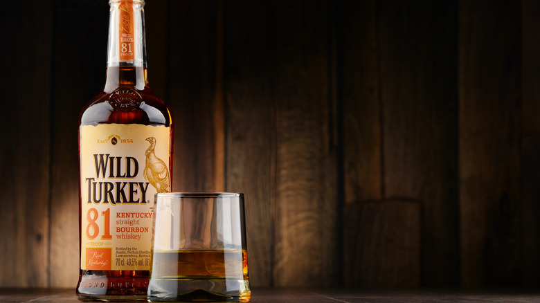 Botella de Wild Turkey junto a una copa de bourbon