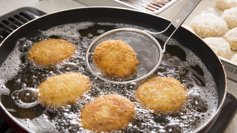 Freír croquetas en una sartén al fuego con aceite poco profundo