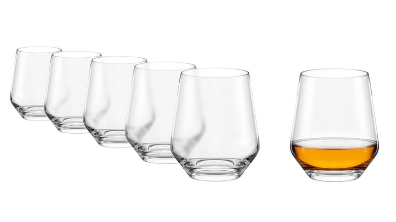 Cinco vasos de whisky Costco vacíos junto a uno con whisky