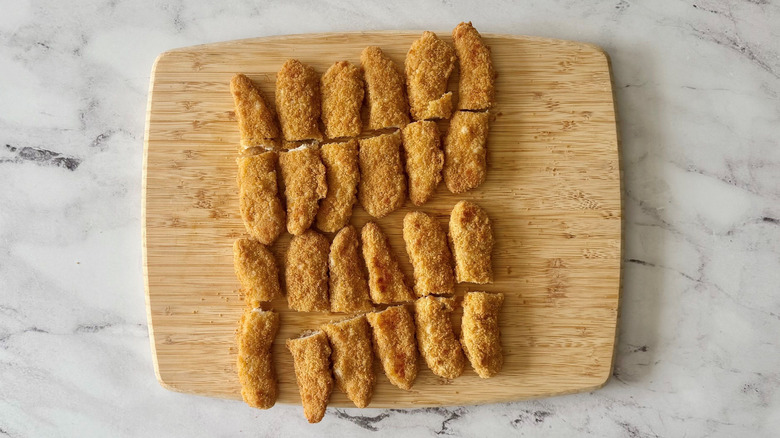 Tiras de pollo a la mitad sobre una tabla para cortar
