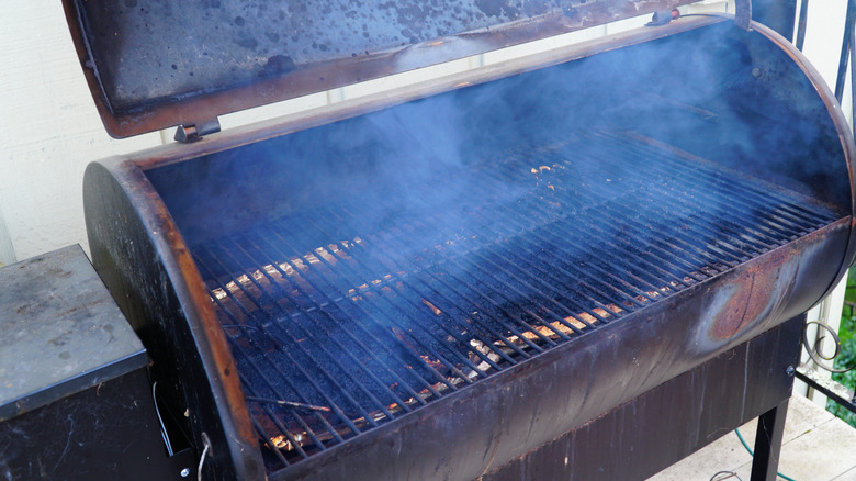 Una parrilla Traeger abierta precalentándose, con humo saliendo de la cámara de cocción