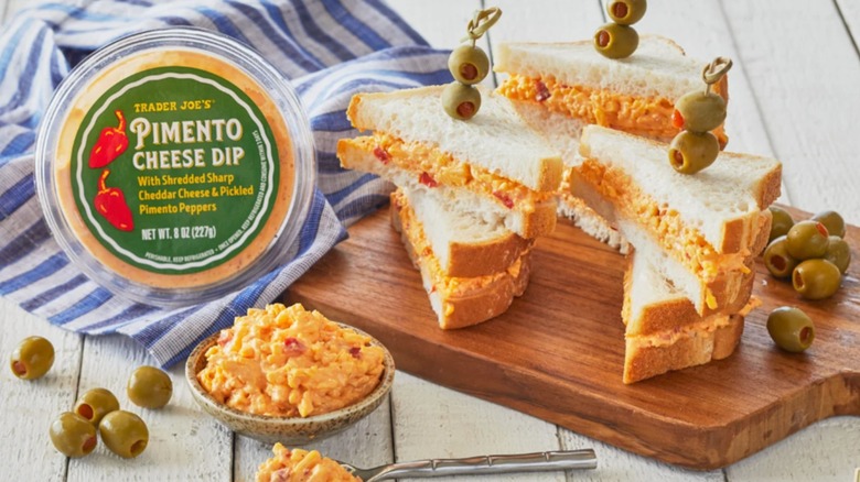 Contenedor de salsa de queso y pimiento Trader Joe's junto a sándwiches hechos con ella