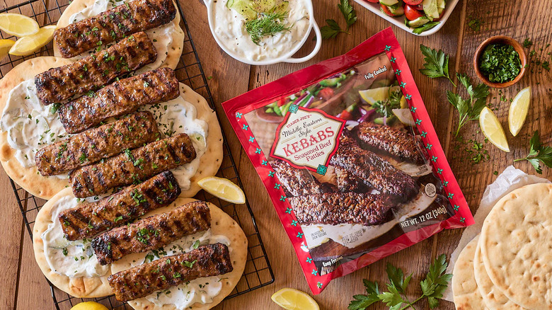 Kebabs del Medio Oriente con pitas sobre una tabla de madera, junto a una bolsa de Kebabs estilo Medio Oriente de Trader Joe's