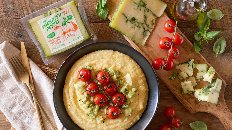 El queso pesto de oveja con comida y cubiertos sobre una mesa de madera