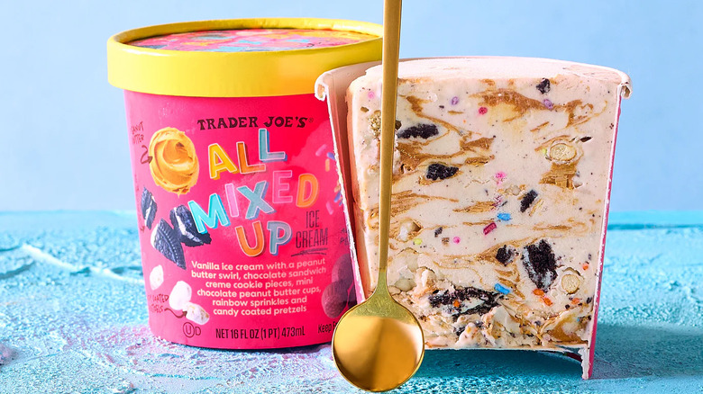 Cartón de helado All Mixed Up abierto, junto a un cartón lleno y una cuchara