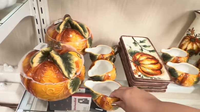Estante de vidrio con tarros de galletas de calabaza, tazones para crema y platos